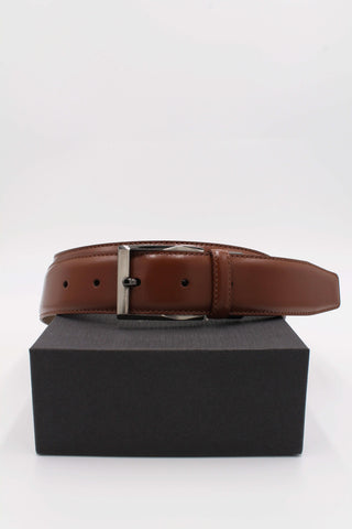 Tan leather belt buckled up with packaging box.